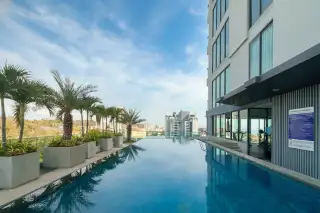 The Point Pratumnak infinity pool on a high floor with palm trees and distant city skyline.