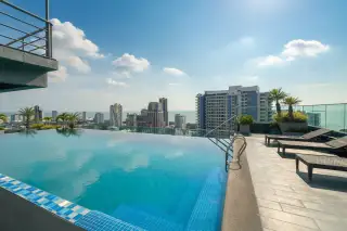 The Point Pratumnak rooftop infinity pool overlooking the Pattaya city skyline and ocean.