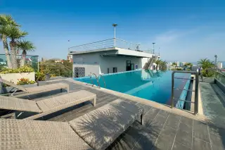 The Point Pratumnak rooftop swimming pool area with sun loungers and a partial city view.