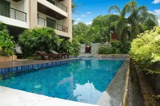The Regent Pratumnak: outdoor swimming pool with blue tiles, lounge chairs, and lush tropical landscaping.