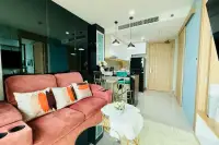 1 Bedroom Condo for Rent at The Riviera Jomtien open-plan living area with pink sofa and kitchen bar