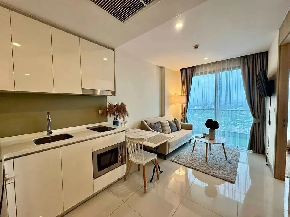 1 Bedroom Condo for Rent at The Riviera Jomtien open-plan kitchen with white cabinetry and living area with city view