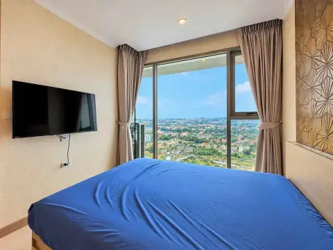 1 Bedroom Condo for Rent at The Riviera Jomtien bedroom with wall-mounted TV and city skyline view