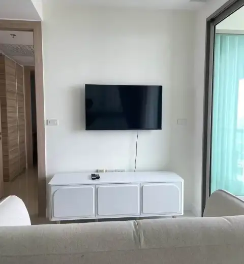1 Bedroom Condo for Rent at The Riviera Jomtien living room with wall-mounted TV and white media console