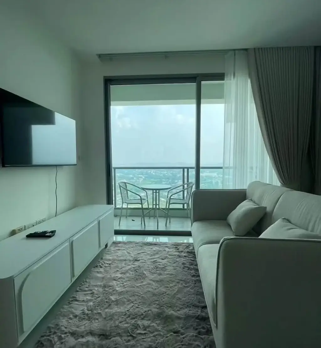 1 Bedroom Condo for Rent at The Riviera Jomtien living room sofa with sheer curtains and dining nook by window
