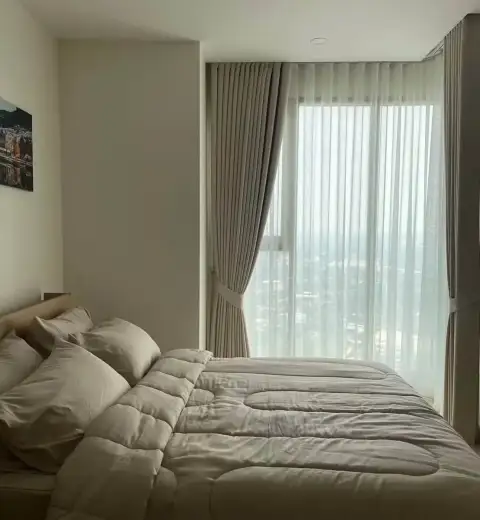 1 Bedroom Condo for Rent at The Riviera Jomtien bedroom with bed, pillows and panoramic window view