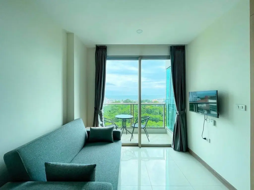 1 Bedroom Condo for Rent at The Riviera Jomtien living room with sofa, TV, and balcony sea view