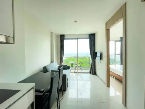 1 Bedroom Condo for Rent at The Riviera Jomtien open-plan living area with dining table and bedroom entrance