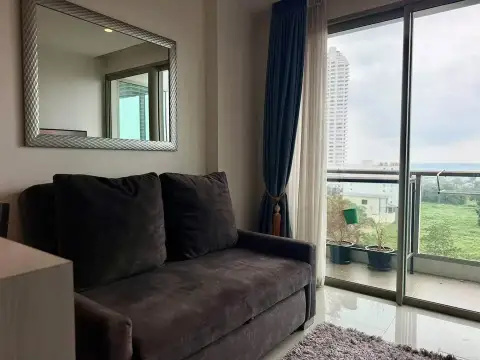 1 Bedroom Condo for Rent at The Riviera Jomtien cozy sofa corner with mirror and balcony overlooking city