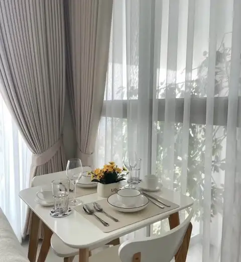 1 Bedroom Condo for Rent at The Riviera Jomtien dining table set for two by sheer curtained window