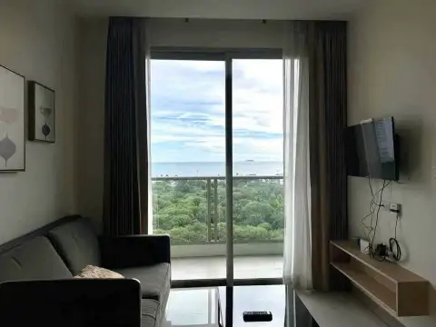 1 Bedroom Condo for Sale at The Riviera Jomtien living room with balcony ocean view and wall-mounted TV