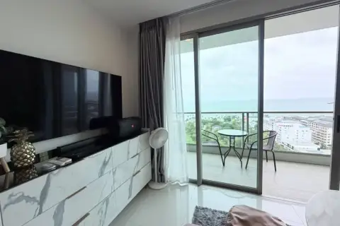 2 Bedroom Condo for Rent at The Riviera Jomtien living room with TV console and balcony sea view