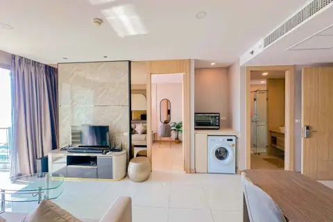 2 Bedroom Condo for Rent at The Riviera Jomtien living area with TV console, washing machine, and bathroom entrance