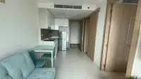 1 Bedroom Condo for Sale at The Riviera Jomtien open-plan kitchen with fridge, dining table and teal sofa