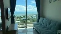 1 Bedroom Condo for Sale at The Riviera Jomtien living area with sea view balcony and teal sofa