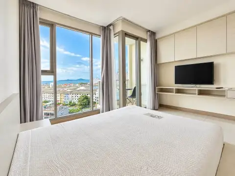 Studio Condo for Sale at The Riviera Jomtien bed facing floor-to-ceiling windows with ocean and city skyline view