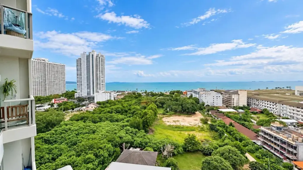 Studio Condo for Rent at The Riviera Jomtien balcony view of sea, high-rise towers and green treetops