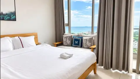 Studio Condo for Rent at The Riviera Jomtien bed and sofa seating area overlooking ocean through floor-to-ceiling window