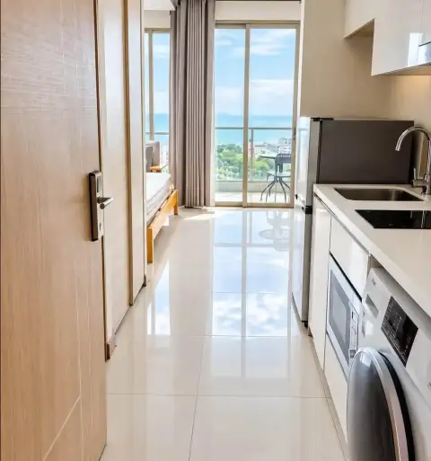 Studio Condo for Rent at The Riviera Jomtien hallway leading to kitchenette with sea view through glass doors