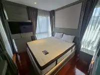 2 Bedroom Condo for Sale at The Senate Residences second bedroom with wall-mounted TV, blackout curtains and wood flooring