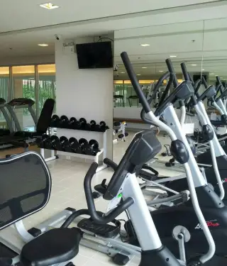 The Trust Condo South Pattaya gym area with elliptical trainers, dumbbell rack, and treadmill