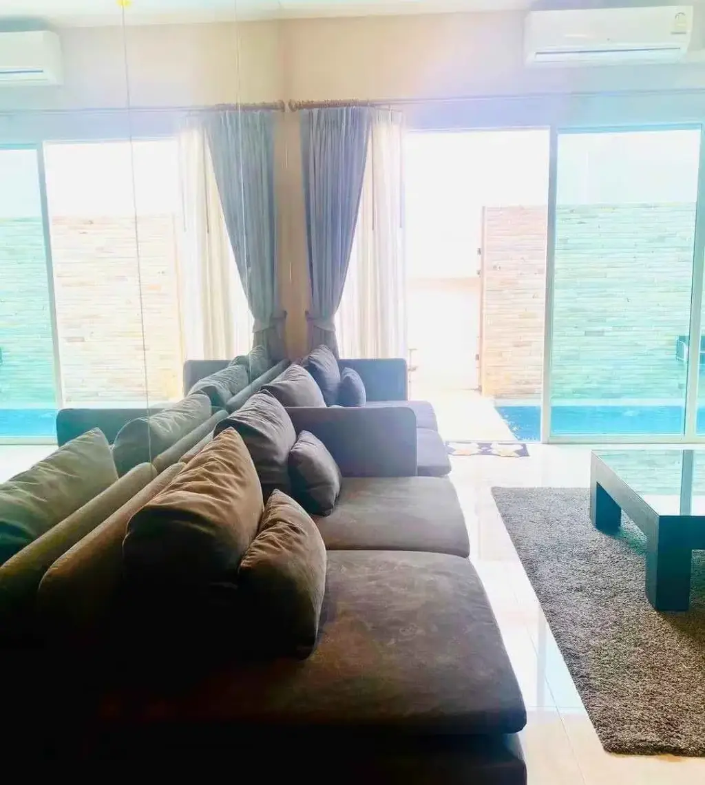 3 Bedroom House for Rent at The Ville Jomtien living room with dark sectional sofa and private pool view