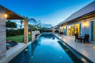 The Ville Jomtien private swimming pool with blue tiles, water feature, and sun loungers.