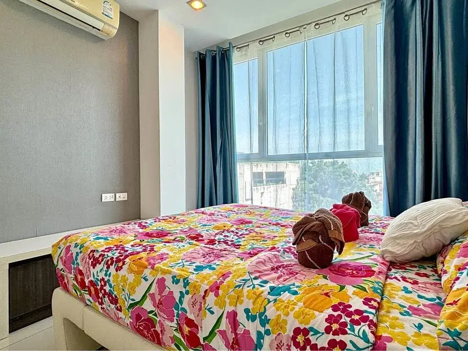 1 Bedroom Condo for Sale at The Vision bedroom with floral bedspread, teal curtains and city view window