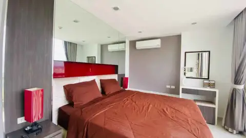 1 Bedroom Condo for Rent at The Vision bedroom with red bedding, mirrored headboard, and dressing table
