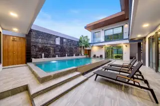 M Mountain Village outdoor pool with jet fountains sunloungers dark marble feature wall at twilight