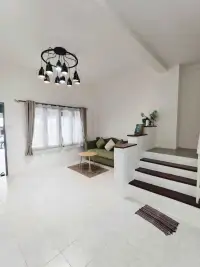 2 Bedroom Townhouse for Rent in East Pattaya living room with green sofa, staircase, and curtained window