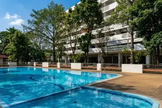 Yensabai Condotel outdoor swimming pool with blue tiles and the white condotel building in the background.