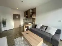 1 Bedroom Condo for Sale at Treetops Condo open-plan kitchenette with gray sofa and wooden coffee table