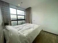 1 Bedroom Condo for Sale at Treetops Condo bedroom with large bed and floor-to-ceiling window city view