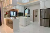 4 Bedroom House for Sale at Chokchai Garden Home 2, modern kitchen with white cabinets, island, stainless steel fridge, and bar.