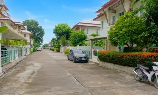 The Villa Rachawadee modern blue house with a dark roof, white trim, air conditioning units, and a fenced front.