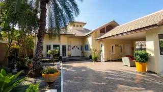 Classic Villa aerial view of the backyard with a swimming pool, green lawn, sun loungers, and palm trees.