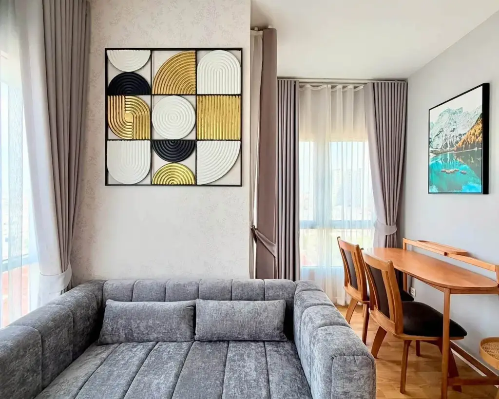2 Bedroom Condo for Rent at Unicca living room with gray sofa, geometric wall art and wooden dining table