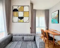 2 Bedroom Condo for Rent at Unicca living room with gray sofa, geometric wall art and wooden dining table