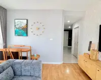 2 Bedroom Condo for Rent at Unicca open living area with sofa, wall clock, sideboard and hallway view