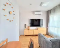 2 Bedroom Condo for Rent at Unicca living room with mounted TV, wooden cabinets and air conditioning unit