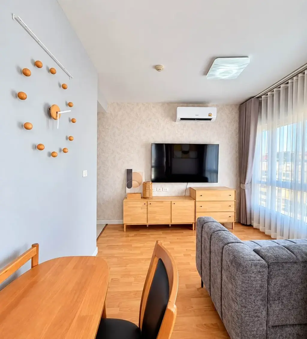 2 Bedroom Condo for Rent at Unicca living room with gray sofa, wall-mounted TV, and wooden dining table