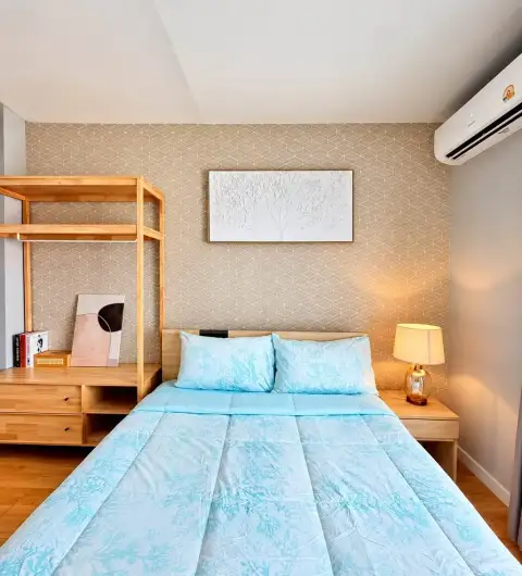 2 Bedroom Condo for Rent at Unicca bedroom with light blue bedspread, bedside lamp, and patterned wallpaper