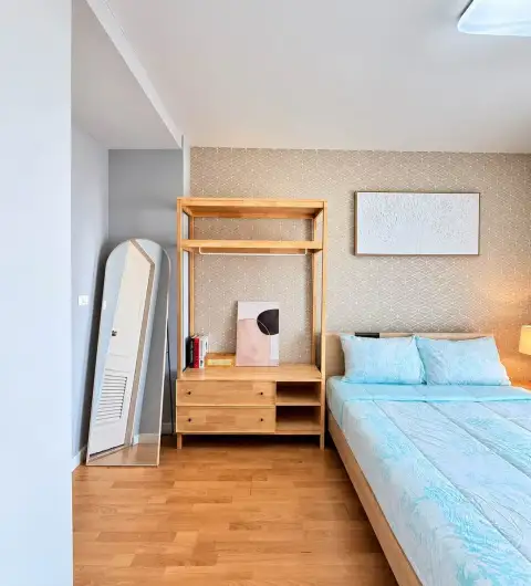 2 Bedroom Condo for Rent at Unicca bedroom with light blue bedding, wooden wardrobe shelf, and full-length mirror