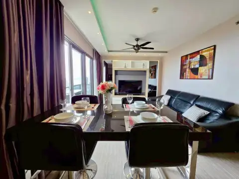 2 Bedroom Condo for Rent at Unixx South Pattaya dining table set for two beside leather sofa and TV unit