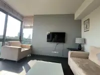 2 Bedroom Condo for Rent at Unixx South Pattaya living room with beige sofas, wall-mounted TV and city view window