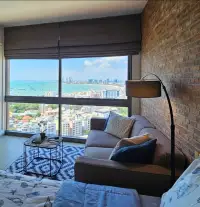 Studio Condo for Rent at Unixx South Pattaya sofa with floor lamp and ocean skyline window view