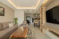 2 Bedroom Condo for Sale at Zensiri Estates and Residences living room with wood TV wall unit, sofa, and open-plan kitchen view