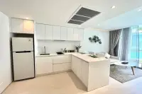 1 Bedroom Condo for Sale at Celine Wongamat white L-shaped kitchen with full-size refrigerator, induction hob, and open living area