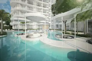 The Coral Pattaya, resort-style swimming pool with submerged lounge areas and palm trees.